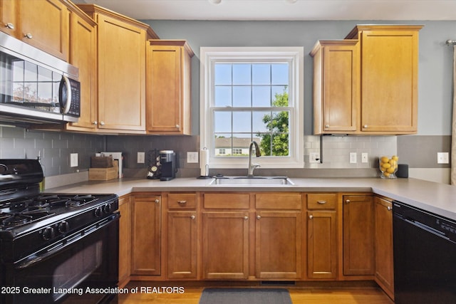 3893 E Plover Pl, East Lansing, MI 48823 - kitchen featuring black appliances, a sink, light countertops, and decorative backsplash