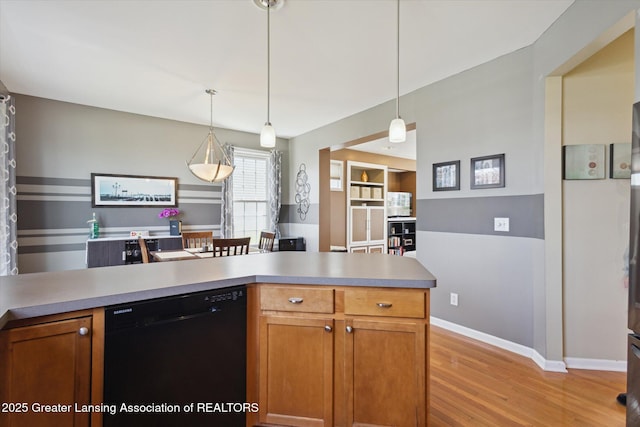 3893 E Plover Pl, East Lansing, MI 48823 - kitchen featuring dishwasher, light wood-style flooring, decorative light fixtures, baseboards, and light countertops