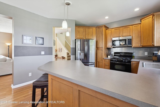 3893 E Plover Pl, East Lansing, MI 48823 - kitchen featuring appliances with stainless steel finishes, a sink, light wood-style flooring, tasteful backsplash, and baseboards