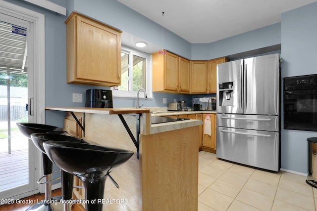 4716 Wainwright Ave, Lansing, MI 48911 - kitchen with stainless steel refrigerator with ice dispenser, oven, light brown cabinetry, light countertops, and a peninsula