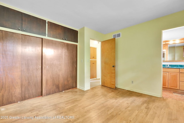 1450 N Hagadorn Rd, East Lansing, MI 48823 - unfurnished bedroom featuring light wood-style flooring, a closet, and baseboards