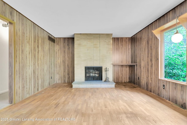 1450 N Hagadorn Rd, East Lansing, MI 48823 - unfurnished living room with wood walls, a fireplace, and wood finished floors