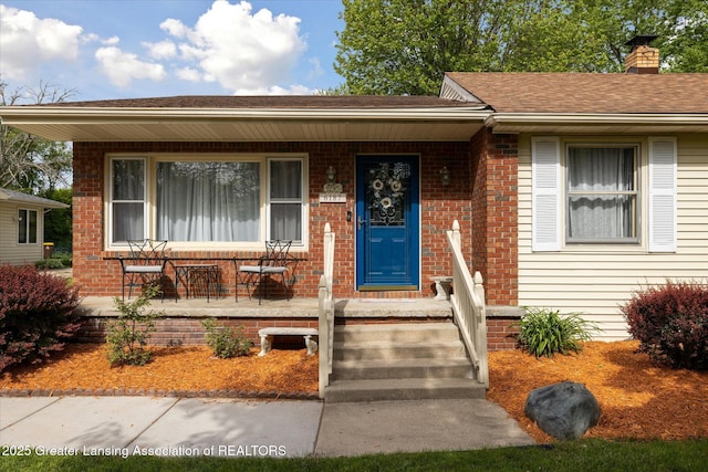 6187 Towar Ave, East Lansing, MI 48823 - view of front of property featuring covered porch, brick siding, a chimney, and a shingled roof