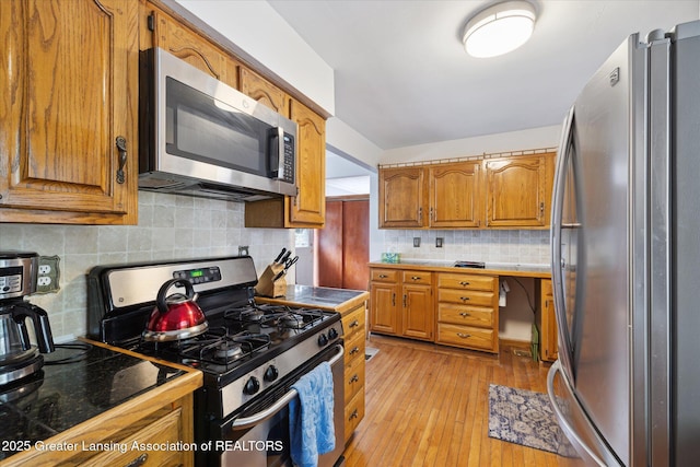 6187 Towar Ave, East Lansing, MI 48823 - kitchen featuring appliances with stainless steel finishes, decorative backsplash, brown cabinets, and light wood-type flooring