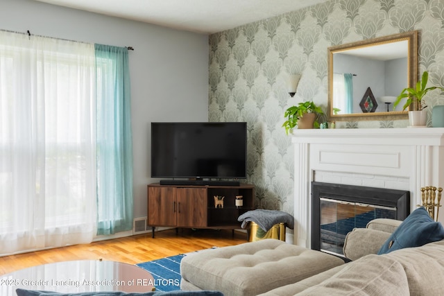 1311 Moores River Dr, Lansing, MI 48910 - living area featuring wallpapered walls, wood finished floors, and a glass covered fireplace
