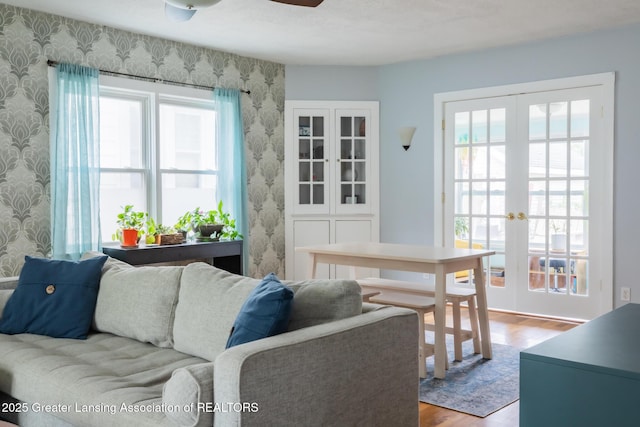 1311 Moores River Dr, Lansing, MI 48910 - living room featuring wallpapered walls, french doors, wood finished floors, healthy amount of natural light, and a ceiling fan