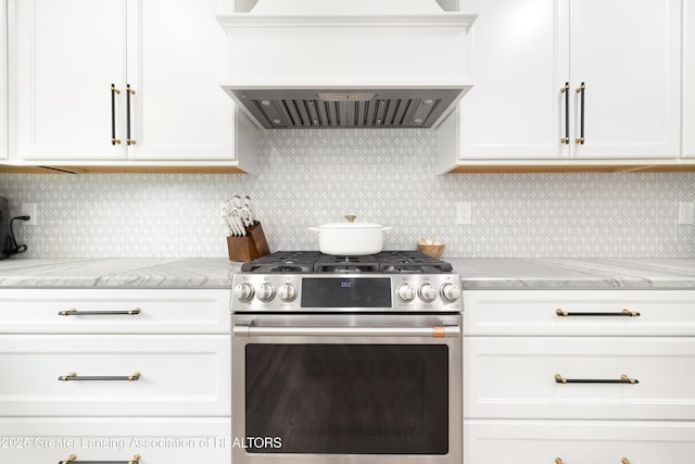 1232 Chemung Forest Dr, Howell, MI 48843 - kitchen featuring stainless steel gas range oven, custom exhaust hood, white cabinets, light stone counters, and backsplash