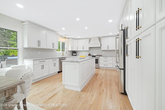 1232 Chemung Forest Dr, Howell, MI 48843 - kitchen with premium range hood, appliances with stainless steel finishes, tasteful backsplash, light wood-style flooring, and white cabinets