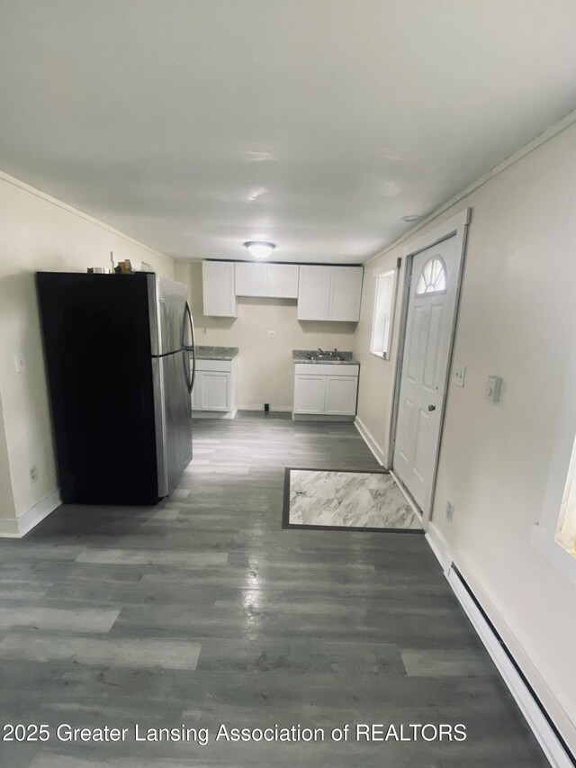 3319 Westmont Ave, Lansing, MI 48906 - kitchen featuring freestanding refrigerator, a baseboard heating unit, white cabinetry, baseboards, and dark wood-style floors