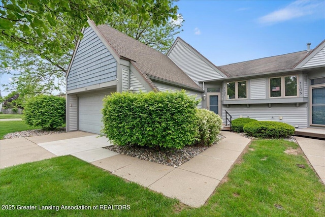 1101 Boulder Ct Unit 48, Lansing, MI 48917 - view of side of property featuring a shingled roof, driveway, and a lawn