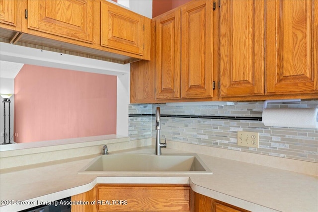 1101 Boulder Ct Unit 48, Lansing, MI 48917 - kitchen with a sink, light countertops, backsplash, and brown cabinetry