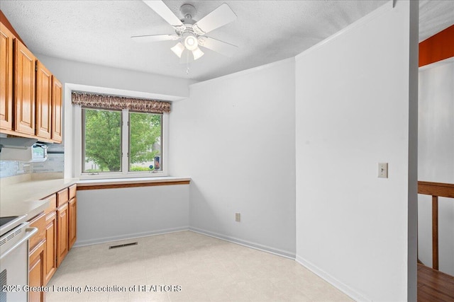 1101 Boulder Ct Unit 48, Lansing, MI 48917 - kitchen featuring ceiling fan, electric stove, a textured ceiling, light countertops, and brown cabinets