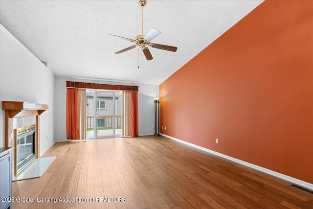 1101 Boulder Ct Unit 48, Lansing, MI 48917 - unfurnished living room with ceiling fan, wood finished floors, a textured ceiling, lofted ceiling, and a tile fireplace