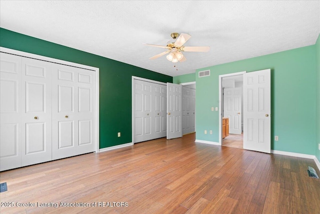 1101 Boulder Ct Unit 48, Lansing, MI 48917 - unfurnished bedroom featuring wood finished floors, multiple closets, baseboards, and a ceiling fan