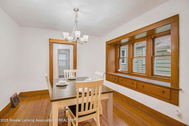2104 Clifton Ave, Lansing, MI 48910 - dining area featuring wood finished floors, a chandelier, a textured ceiling, and baseboards