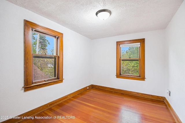 2104 Clifton Ave, Lansing, MI 48910 - unfurnished room featuring healthy amount of natural light, wood finished floors, baseboards, and a textured ceiling