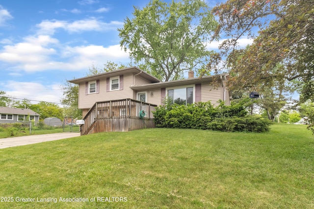 1021 Kendon Dr, Lansing, MI 48910 - split level home with a chimney, a front lawn, concrete driveway, and a deck
