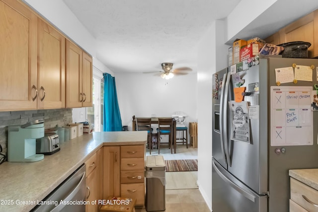 1021 Kendon Dr, Lansing, MI 48910 - kitchen with appliances with stainless steel finishes, a ceiling fan, a peninsula, tasteful backsplash, and light countertops