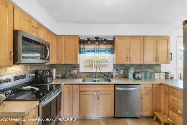 1021 Kendon Dr, Lansing, MI 48910 - kitchen with stainless steel appliances, a sink, light brown cabinets, light countertops, and decorative backsplash