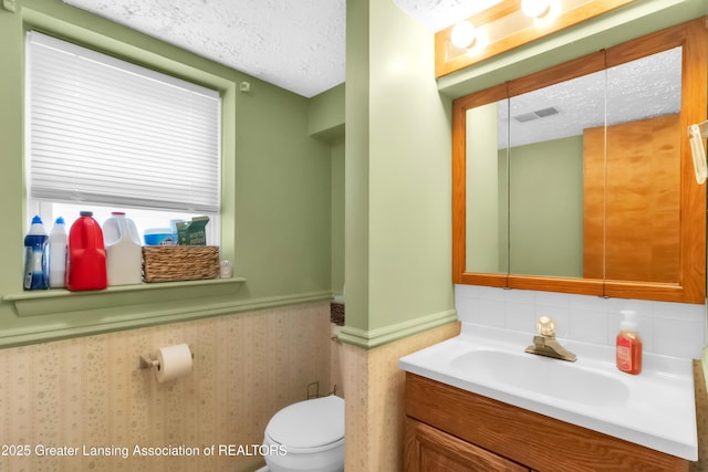 1021 Kendon Dr, Lansing, MI 48910 - bathroom with toilet, vanity, a wainscoted wall, and a textured ceiling