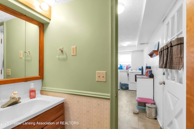 1021 Kendon Dr, Lansing, MI 48910 - bathroom featuring washer / clothes dryer, vanity, a textured ceiling, and tile patterned floors