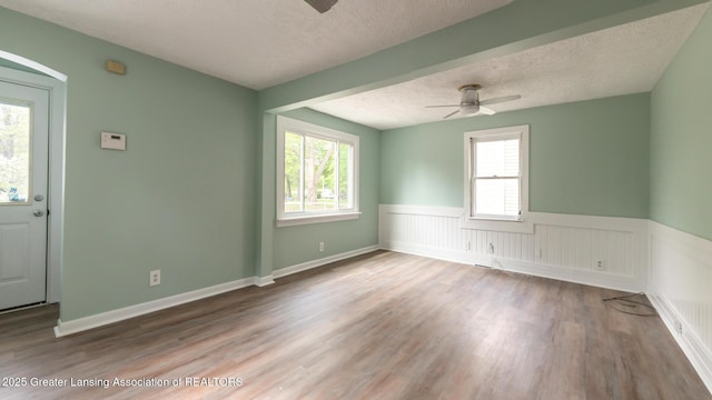 621 Ridgewood Ave, Lansing, MI 48910 - spare room with a ceiling fan, a textured ceiling, wood finished floors, and a wainscoted wall