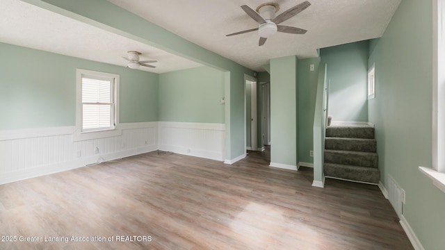 621 Ridgewood Ave, Lansing, MI 48910 - unfurnished room with a ceiling fan, stairway, a wainscoted wall, wood finished floors, and a textured ceiling