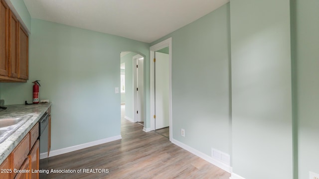 621 Ridgewood Ave, Lansing, MI 48910 - kitchen featuring arched walkways, brown cabinets, light wood finished floors, and baseboards