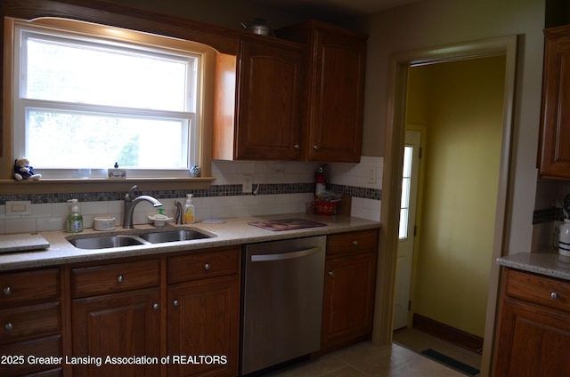 1161 Rebecca Rd, East Lansing, MI 48823 - kitchen featuring dishwasher, a sink, tasteful backsplash, brown cabinetry, and light stone counters