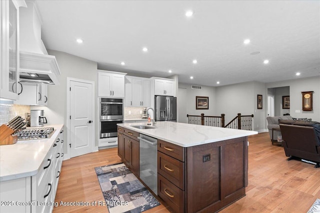 6619 Windford Ln, Grand Ledge, MI 48837 - kitchen featuring appliances with stainless steel finishes, a sink, custom exhaust hood, white cabinets, and backsplash