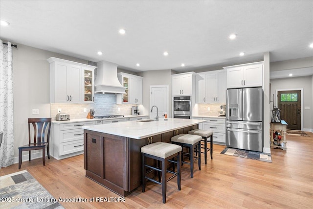 6619 Windford Ln, Grand Ledge, MI 48837 - kitchen featuring appliances with stainless steel finishes, custom range hood, a sink, a breakfast bar area, and tasteful backsplash