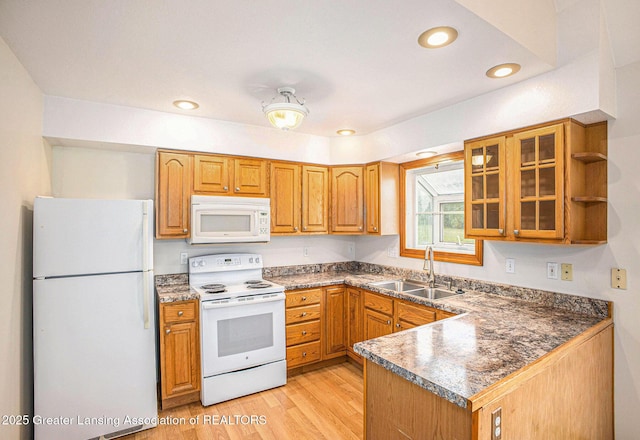 3037 Hawley Rd, Leslie, MI 49251 - kitchen with white appliances, a sink, light wood-style floors, brown cabinets, and a peninsula