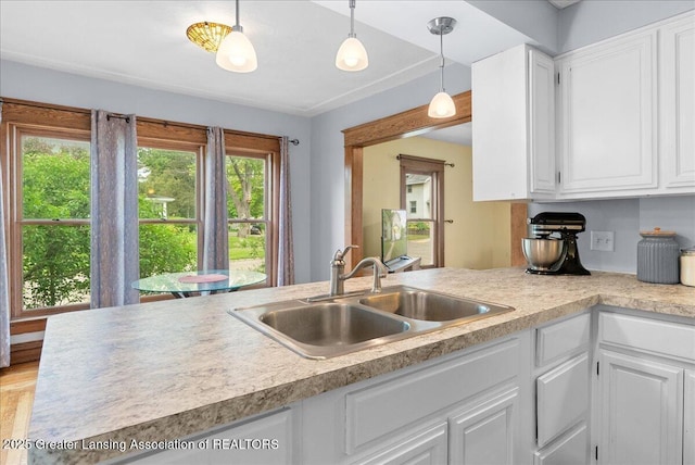 329 Smith Ave, Lansing, MI 48910 - kitchen featuring a sink, white cabinets, light countertops, and hanging light fixtures