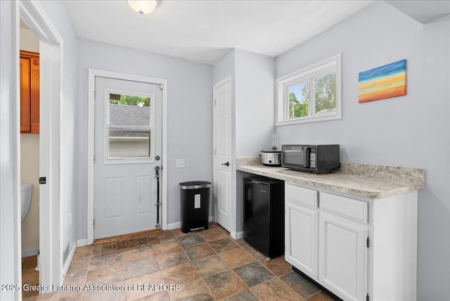 329 Smith Ave, Lansing, MI 48910 - kitchen with black microwave, refrigerator, light countertops, baseboards, and white cabinetry