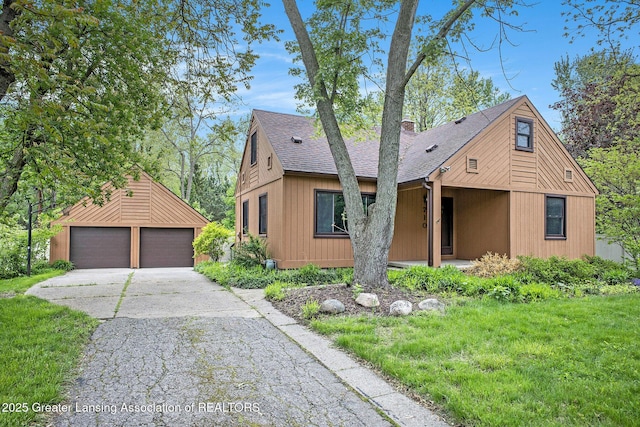 710 Gainsborough Dr, East Lansing, MI 48823 - view of front of house with a shingled roof, a detached garage, an outbuilding, and a chimney