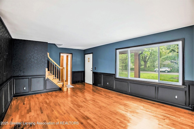 710 Gainsborough Dr, East Lansing, MI 48823 - unfurnished living room featuring stairs, a wainscoted wall, wood finished floors, and a decorative wall