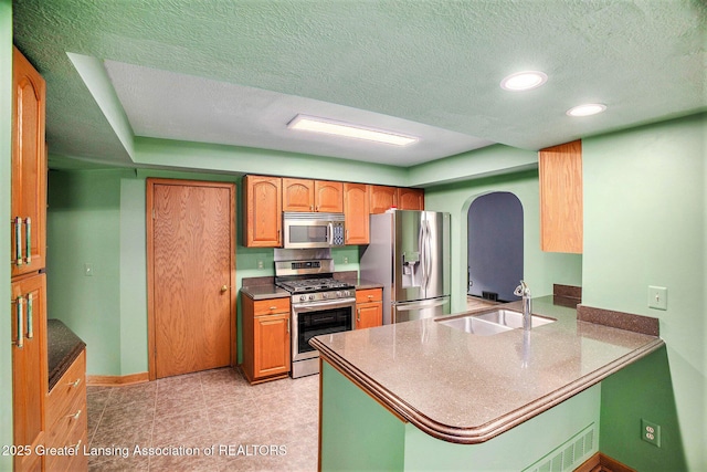 710 Gainsborough Dr, East Lansing, MI 48823 - kitchen with appliances with stainless steel finishes, a sink, arched walkways, a peninsula, and baseboards