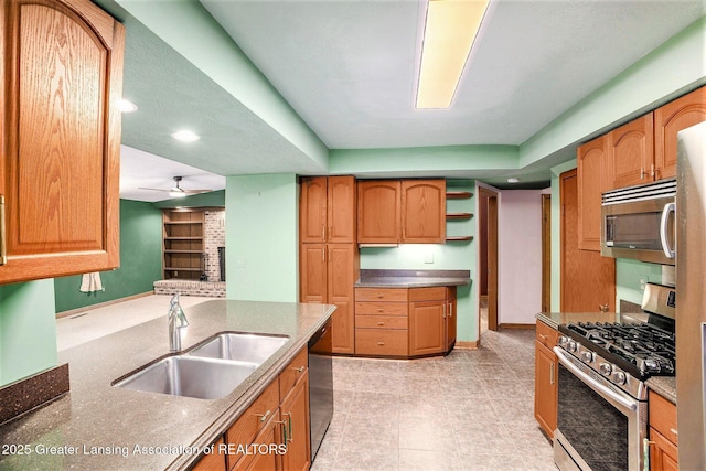710 Gainsborough Dr, East Lansing, MI 48823 - kitchen featuring appliances with stainless steel finishes, a sink, a fireplace, baseboards, and a ceiling fan