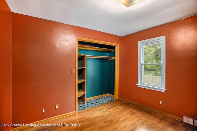 710 Gainsborough Dr, East Lansing, MI 48823 - unfurnished bedroom with wood finished floors, baseboards, and a closet