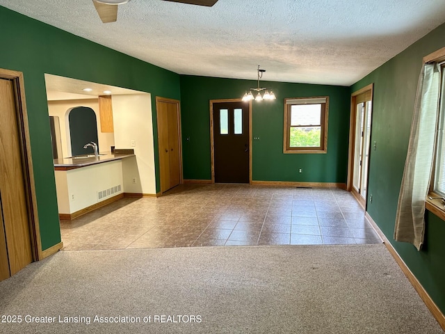 710 Gainsborough Dr, East Lansing, MI 48823 - carpeted entrance foyer with a textured ceiling, a chandelier, and tile patterned floors