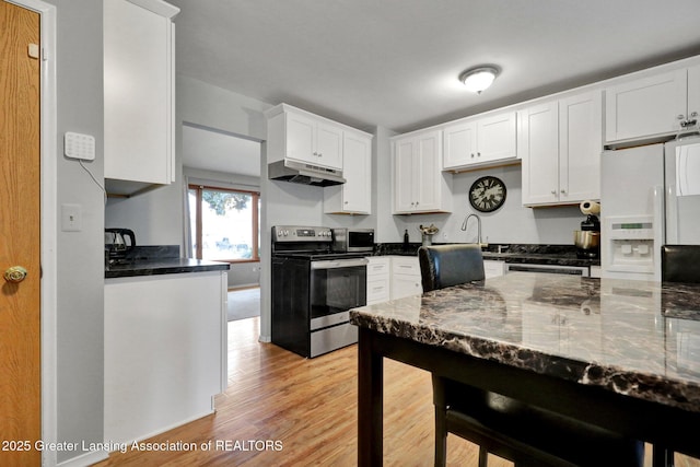 1580 Grayfriars Ave, Holt, MI 48842 - kitchen featuring appliances with stainless steel finishes, under cabinet range hood, light wood-style floors, white cabinetry, and dark stone countertops