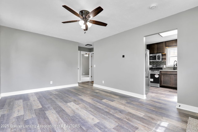 209 Haze St, Lansing, MI 48917 - unfurnished living room with ceiling fan, wood finished floors, baseboards, and a sink