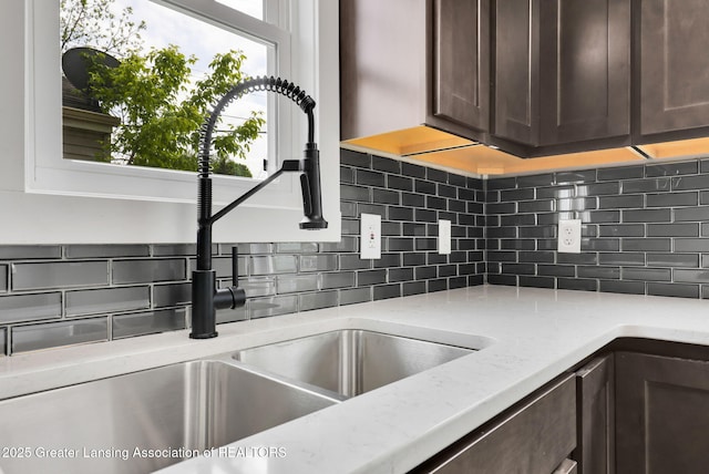 209 Haze St, Lansing, MI 48917 - kitchen featuring dark brown cabinets, decorative backsplash, a sink, and light stone countertops