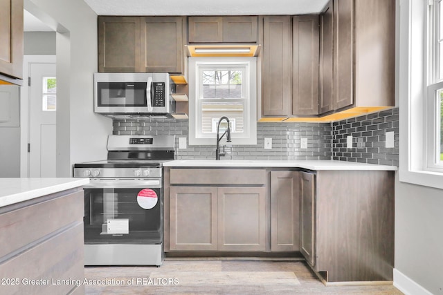 209 Haze St, Lansing, MI 48917 - kitchen featuring appliances with stainless steel finishes, tasteful backsplash, light wood finished floors, and light countertops