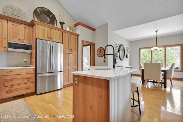 4740 Round Lake Rd, Laingsburg, MI 48848 - kitchen featuring appliances with stainless steel finishes, light wood finished floors, a chandelier, backsplash, and lofted ceiling