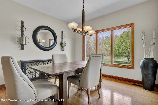 4740 Round Lake Rd, Laingsburg, MI 48848 - dining space with a chandelier, light wood-style floors, and baseboards