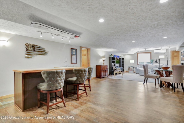 4740 Round Lake Rd, Laingsburg, MI 48848 - dining area with wet bar, light wood-style floors, baseboards, a textured ceiling, and recessed lighting