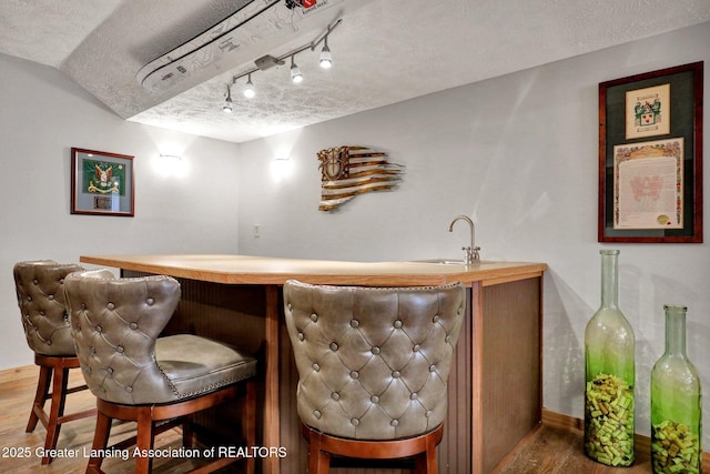 4740 Round Lake Rd, Laingsburg, MI 48848 - indoor wet bar with wood finished floors, a textured ceiling, and baseboards