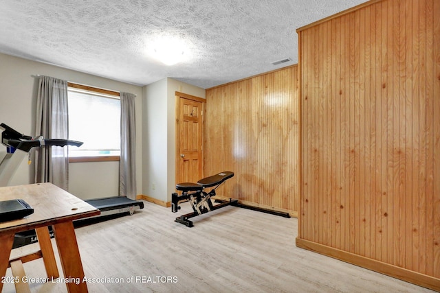 4740 Round Lake Rd, Laingsburg, MI 48848 - exercise area featuring wood finished floors, wood walls, baseboards, and a textured ceiling