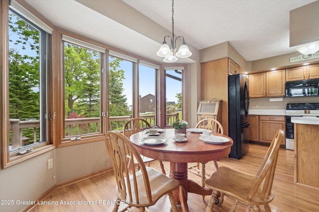 10949 Lakeside Dr, Perrinton, MI 48871 - dining area featuring healthy amount of natural light, light wood-style flooring, baseboards, a chandelier, and a textured ceiling